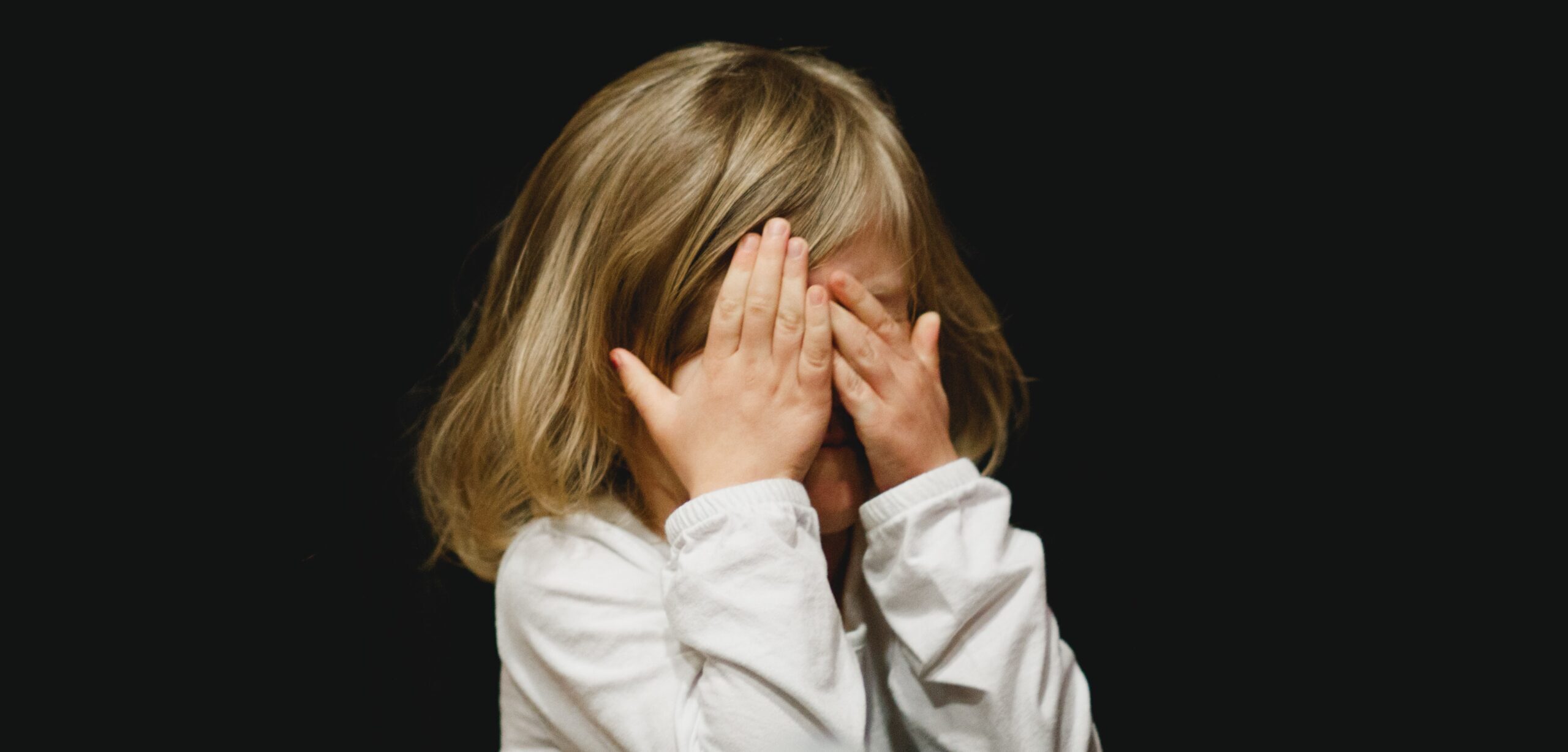 Little girl covering face with hands
