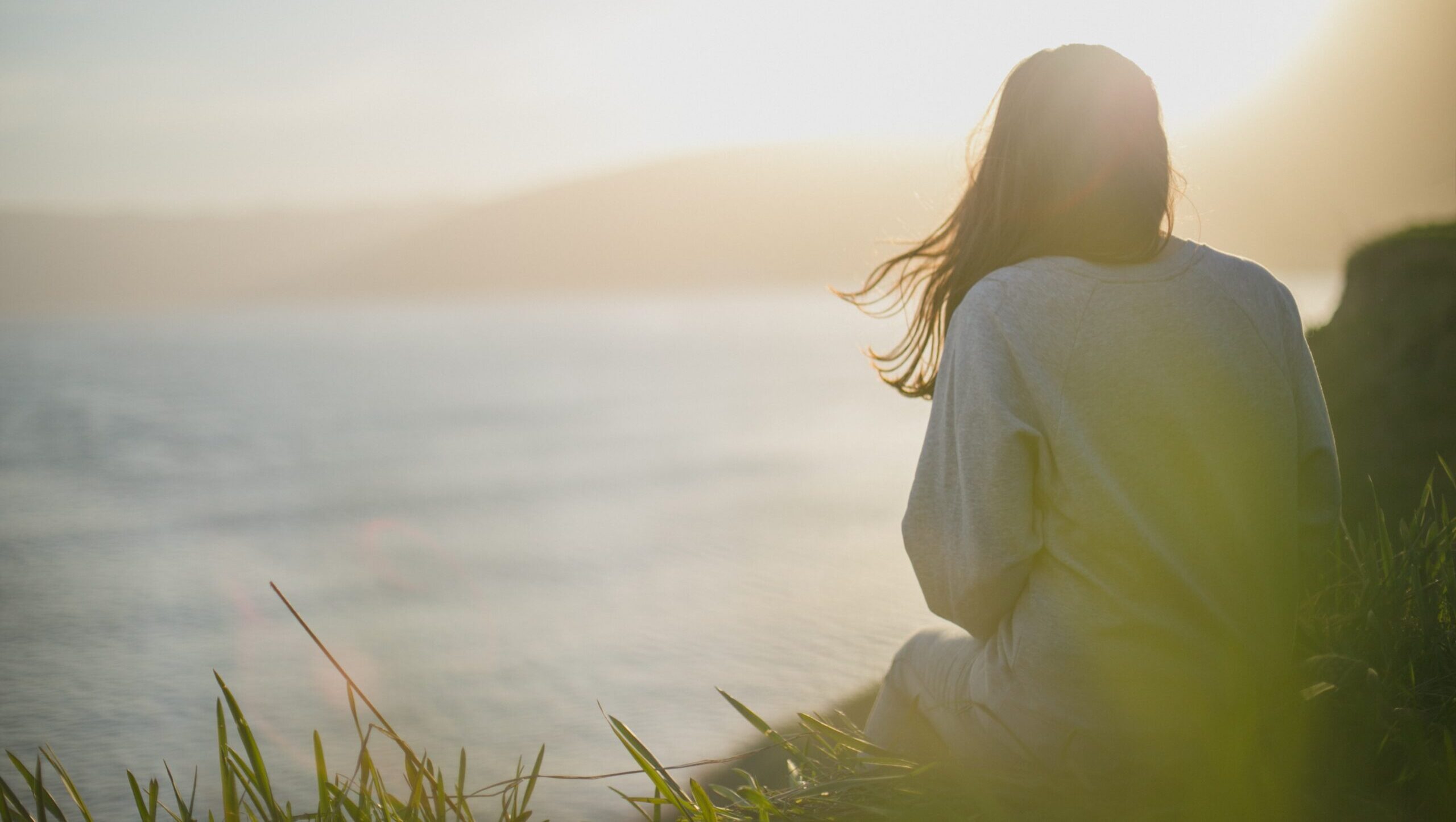 Woman sitting near a lake at sunset