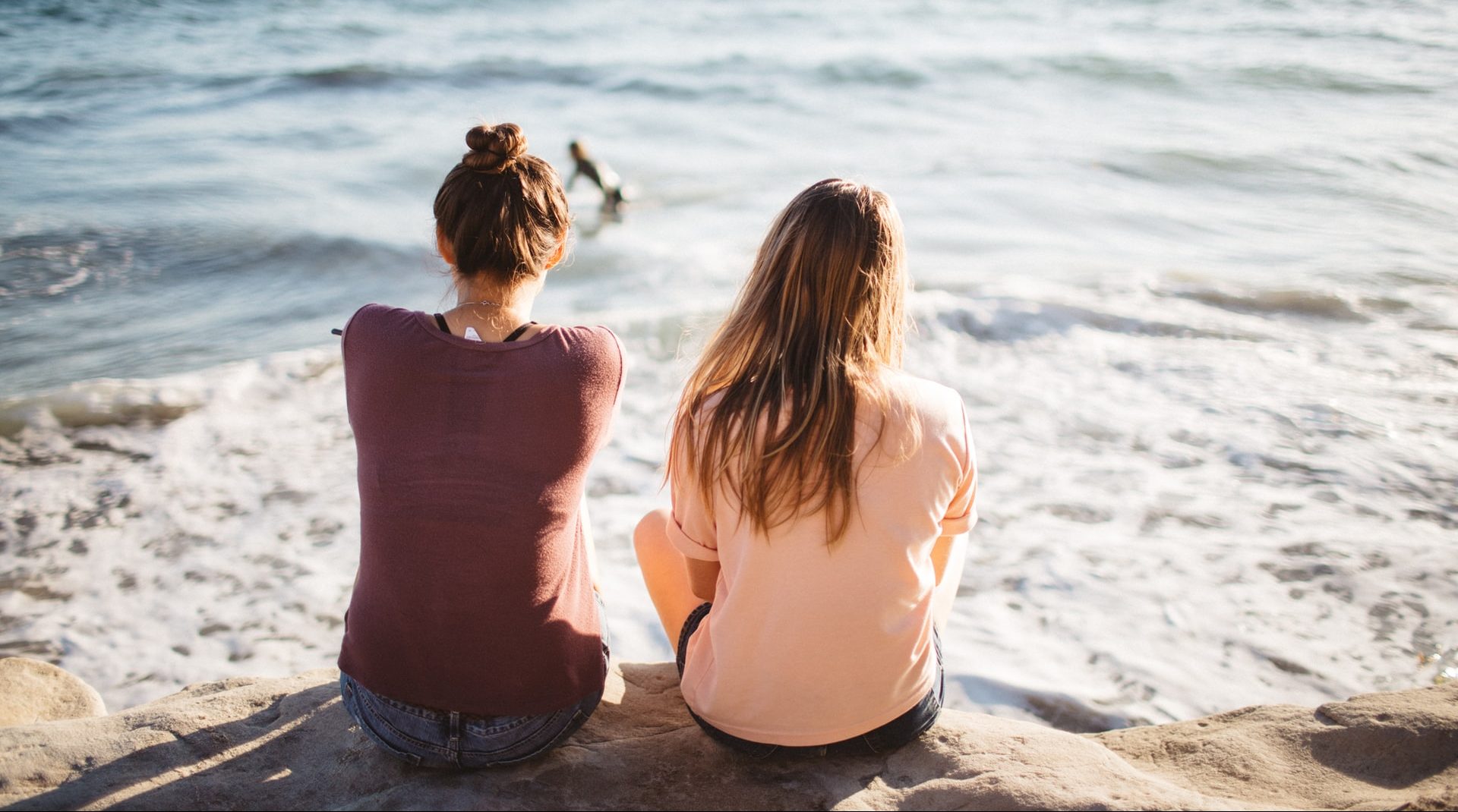 two women sitting on the beach