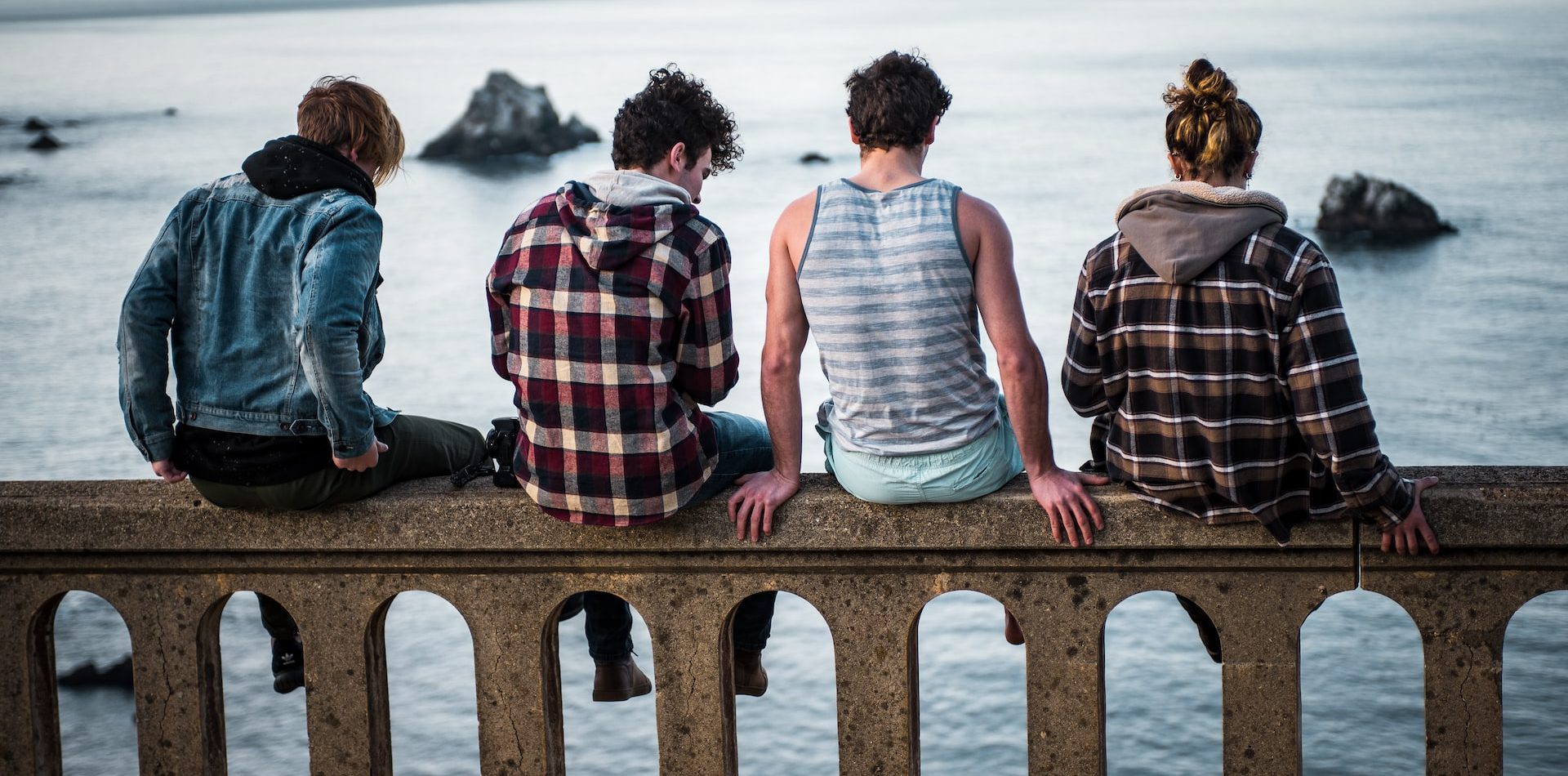 four people sitting on a railing