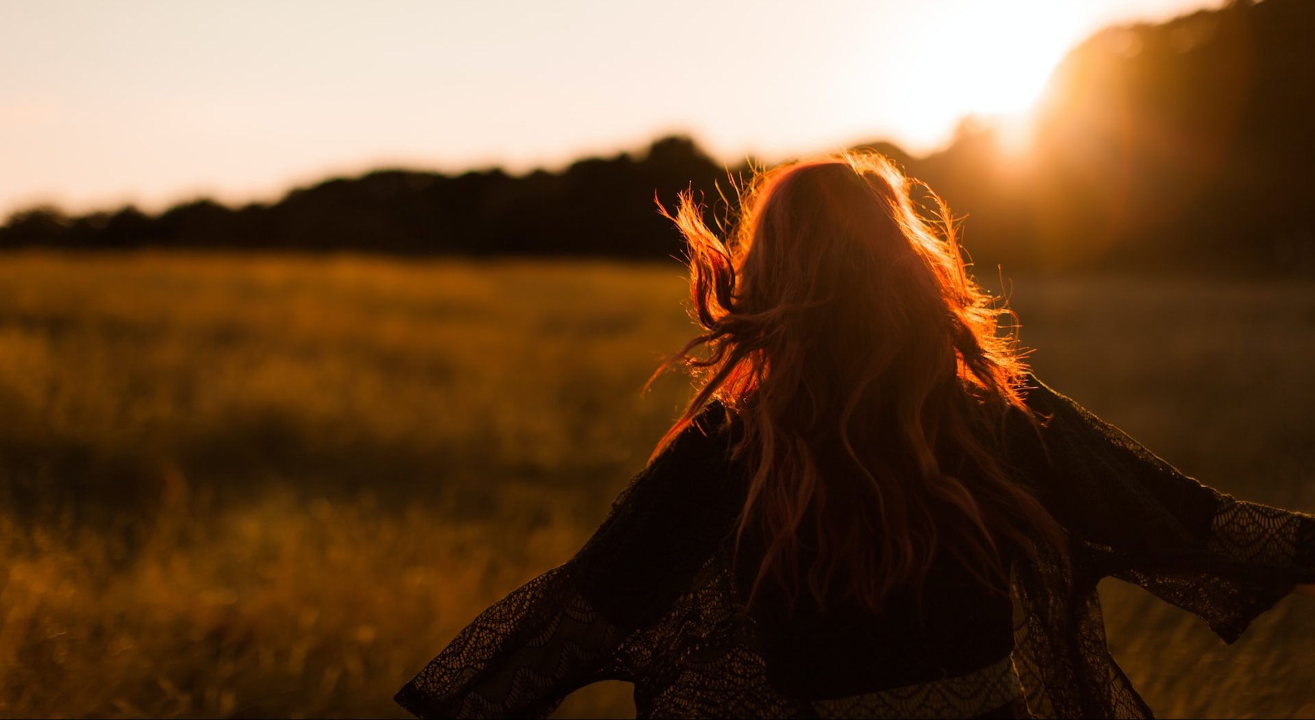 woman running through a field at sunset